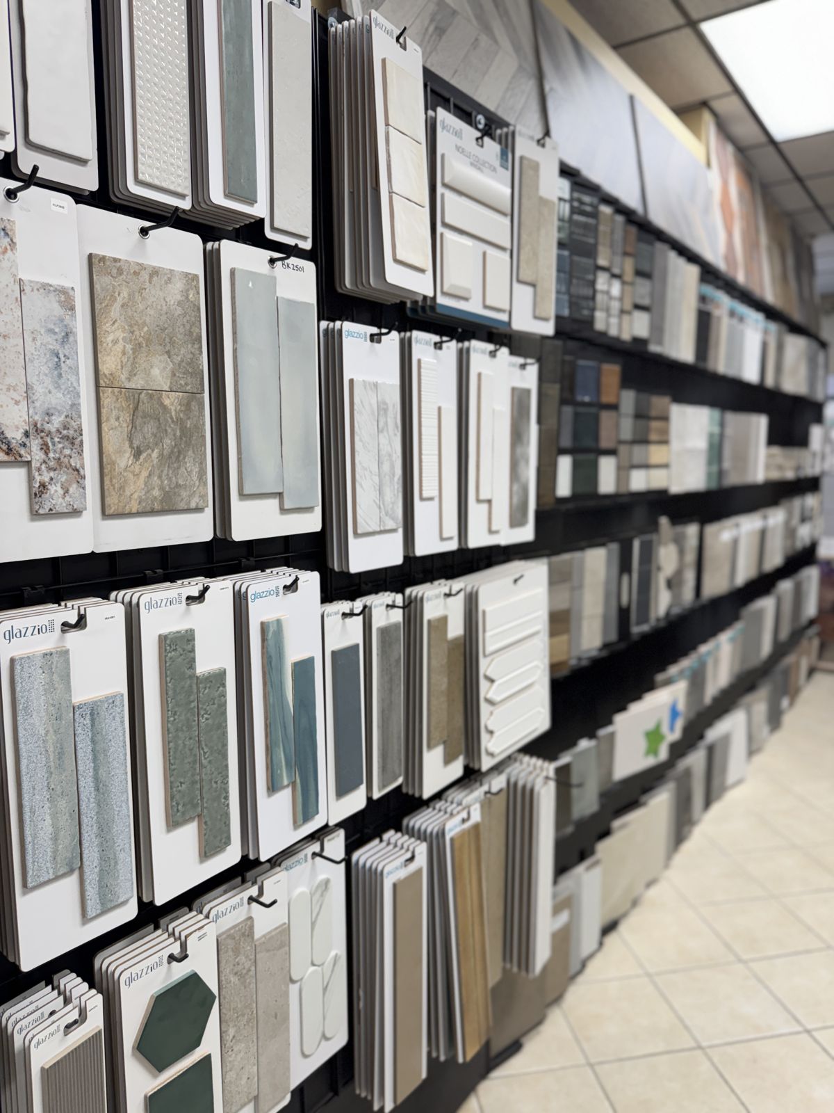 A wall of Glazzio and other tile sample boards: subway, zellige-style, hexagon, and stone-look tile